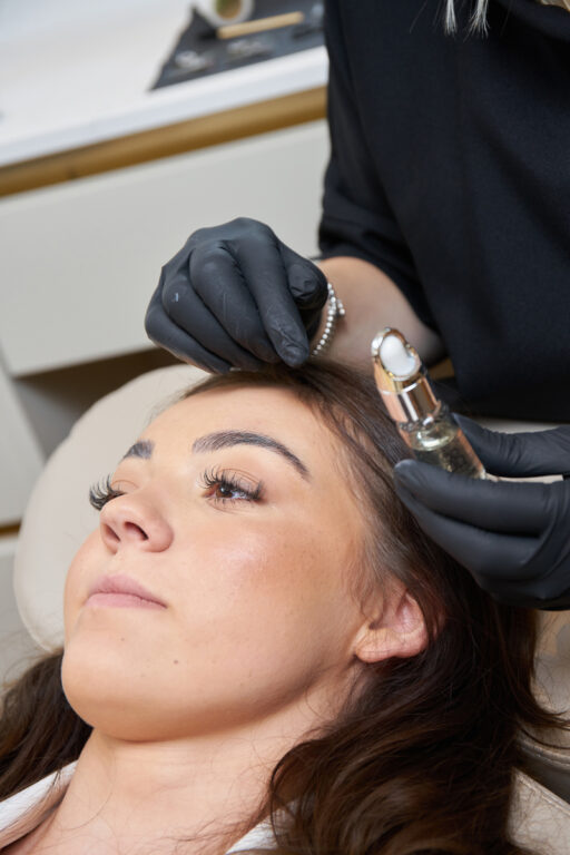 A woman's face, her eyebrows being shaped by a brow artist.