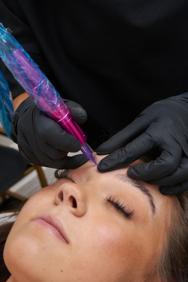 Woman getting her eyebrows shaped and microblading eyebrows.