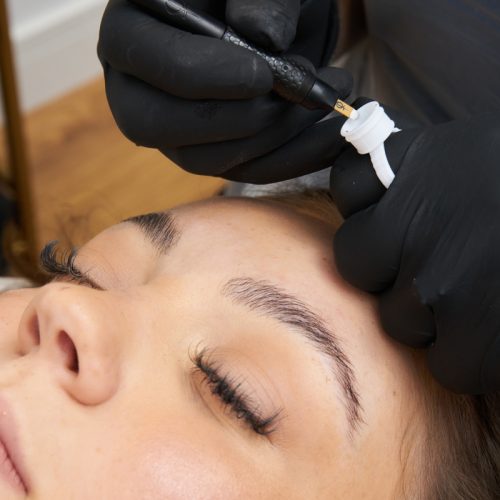 Woman getting her eyebrows microbladed by a professional. Microblading Courses